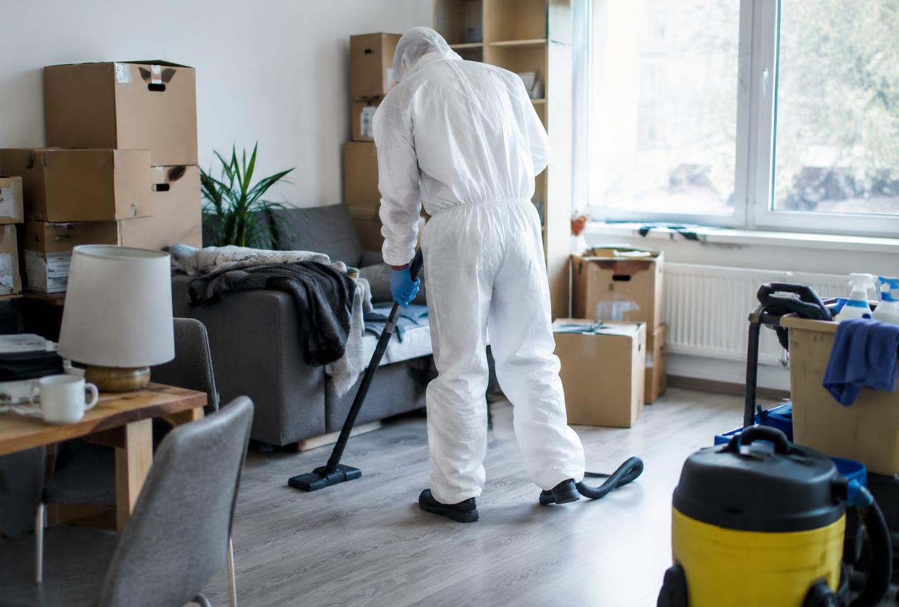 Mitarbeiter in Schutzkleidung reinigt gründlich eine Wohnung